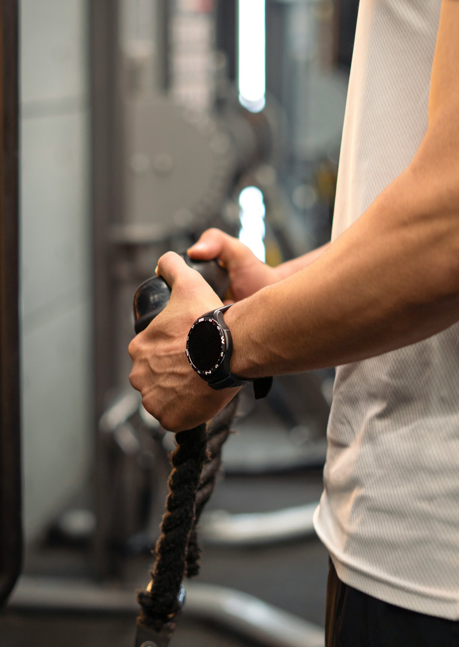 Hände greifen den Griff eines Trainingsgeräts mit Seilzug — Detailaufnahme während des aktiven Trainings